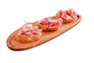 Pişmiş jambon taze otlarla kaplı gevrek ekmek parçaları üzerinde güzelce düzenlenmiştir. Bu iştah açıcı tapas yemeği İspanyol mutfağını ön plana çıkarıyor ve paylaşmak için mükemmel..