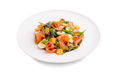 Tütsülenmiş somon, karışık yeşiller, otlar ve beyaz bir tabakta ustalıkla hazırlanmış vişneli domateslerden oluşan canlı bir yemek. Bu taze salata vitrinleri renkli malzemeler..