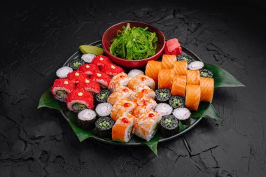 A beautifully arranged sushi platter showcases a variety of sushi rolls, including colorful maki and nigiri, garnished with seaweed and pickled ginger. A fresh seaweed salad adds to the presentation. clipart