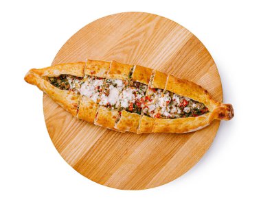 Uzun, çıtır çıtır çıtır çıtır bir pide lezzetli malzemelerle doludur, erimiş peynirle kaplıdır ve davetkar bir restoranda yuvarlak bir ahşap tahtada sunulur..