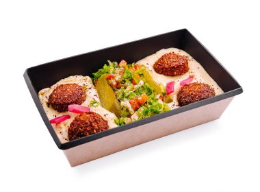 Renkli bir falafel tabağında çeşitli taze sebzeler, krem sosu ve lezzetli bir yemek için mükemmel bir konteynır içinde süslenmiş taze falafel topları bulunur..