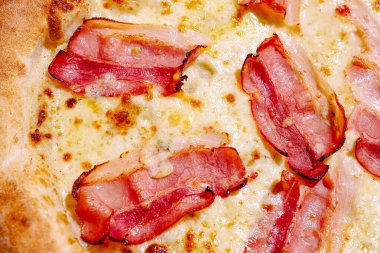 Lezzetli bir pizzada erimiş peynirin üzerinde kıtır kıtır pastırma dilimleri bulunur. Altın hamuru mükemmel pişmiş. Civardaki herkes bir dilim yemek ister..