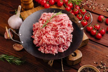 Taze doğranmış etin cömert bir kısmı kırsal bir ahşap masada oturur. Etrafında taze domatesler, sarımsak ve baharatlar var. Canlı bir yemek atmosferi yaratıyorlar..