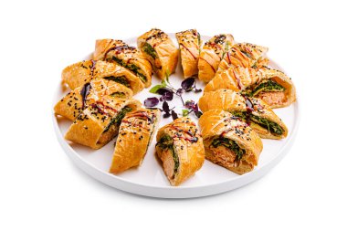 Güzel düzenlenmiş bir tabakta çeşitli lezzetli hamur işleri, taze yeşillikler, aromatik otlar ve çeşitli baharatlar sergileniyor..