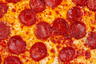Yeni pişmiş pepperonili bir pizza sıcak ve hazır, köpüren peynirini ve baharatlı pepperonisini sergiliyor. Bu yemek, yemek zamanı paylaşmak için idealdir..