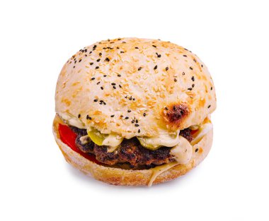 Lezzetli bir hamburgerde ızgara köfte, taze domates, turşu ve kremalı sos vardır, hepsi hafif kızarmış susamlı bir çöreğin içinde hafif bir arkaplan üzerine kuruludur..