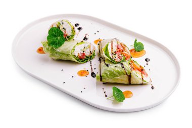 Taze malzemelerle dolu lezzetli sebze dürümleri gösterişli beyaz bir tabakta sanatsal olarak düzenlenir. Garnitürler sunuma renk ve tat katar. Mutfak zevkini gözler önüne serer..