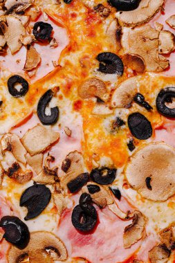 Renkli bir pizza, dilimlenmiş mantarlar ve siyah zeytinler de dahil olmak üzere çeşitli malzemeler sergiler..