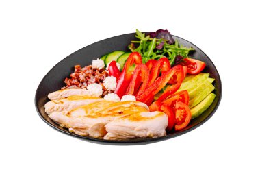 Besleyici bir yemekte canlı kırmızı biberler, salatalık dilimleri ve yapraklı yeşilliklerle ızgara tavuk bulunur. Yemek kırmızı kinoa ve keskin peynirle tamamlanıyor..