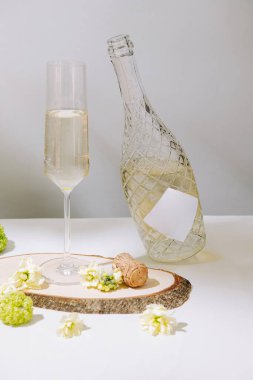 A sparkling beverage rests in a tall glass beside a rustic wooden slice. Fresh flowers and champagne corks add a touch of charm to the peaceful arrangement. clipart