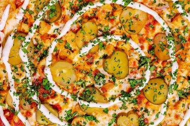 Renkli bir pizza düzeninde turşular, otlar ve erimiş peynir ve çıtır çıtır ekmek üzerine kremalı bir sos ile yaratılmış bir spiral tasarım yer alır. Ortam davetkar ve iştah açıcı..