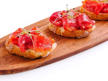 Renkli malzemelerle kaplı üç parça kızarmış ekmek ahşap bir tepside düzenlenir. Bu iştah açıcı yemek harika bir lezzet karışımı paylaşım için mükemmel..