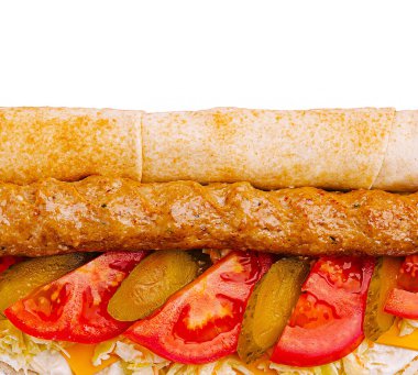 Yumuşak et, canlı domates, gevrek turşu ve öğütülmüş marul ile dolu ağız sulandırıcı bir kebap..