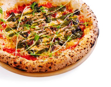 A delicious pizza topped with green pesto, olives, and fresh herbs sits on a wooden serving platter. The golden crust is perfectly baked, showcasing artisanal quality. clipart