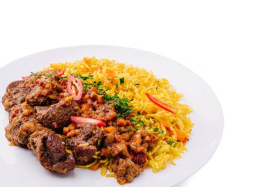 Lezzetli bir et yemeğinin yanında taze sebzelerle süslenmiş canlı bir baharatlı pirinç sunulur. Bu renkli tabakta aroma ve aromaların bir karışımı sergileniyor..