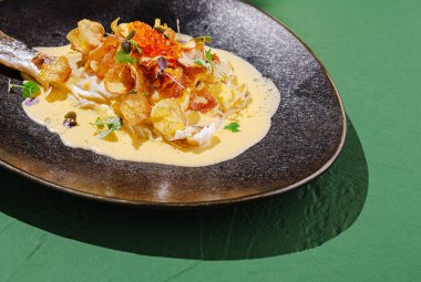 Çok güzel kaplanmış bir gurme vitrinleri çıtır çıtır cipsler ve canlı süslemelerle süslenmiş taze balıklar. Yemek koyu yeşil bir tabakta servis edilir..