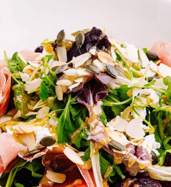 Canlı bir salata, taze yeşillik, dilimlenmiş badem ve hafif soslu kabak çekirdeği karışımı. Yemek ya da öğle yemeği için lezzetli ve besleyici bir seçenek..