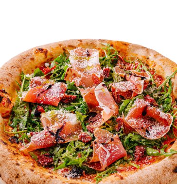Taze roka, ince dilimlenmiş prosciutto ve güneşte kurutulmuş domatesli lezzetli bir pizza. İçinde çıtır çıtır bir kabuk var ve üzerine rendelenmiş peynir serpiştiriliyor..