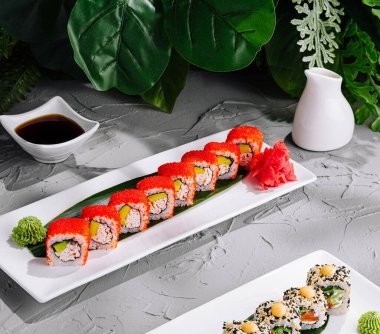 Çağdaş bir tabakta soya sosu eşliğinde balık yumurtası ile kaplı nefis California dürümleri.