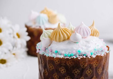 Pastayla süslenmiş nefis bir paskalya pastasına yakın plan. Pasta, pastadan yapılmış öpücükler ve arkaplanda çiçekler.