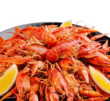 Limon dilimleriyle süslenmiş taze pişmiş kırmızı kerevit dolu canlı bir tabak. Deniz ürünleri yemeği, yemek hazırlama ve tatların toplanma için mükemmel olduğunu vurgular.