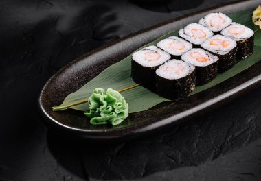 Koyu bir tabakta zencefil ve wasabi ile suşi rulolarının zarif sunumu