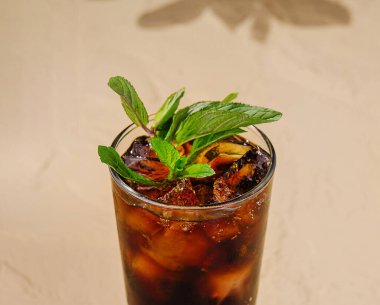 Buzlu ve nane yapraklı bir bardak kola masanın üzerinde duruyor.