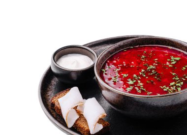Bir kase canlı pancar çorbası, üzerinde otlar, yanında da bir dilim ekmek ve küçük bir tabak krema. Sıcak bir toplantı için mükemmel bir yemek..