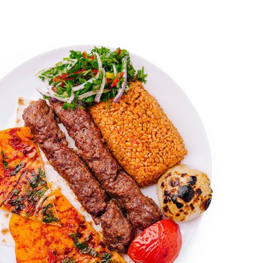 Savor a plate featuring tender grilled kebabs accompanied by spiced rice, grilled vegetables, and a fresh salad. The vibrant colors and rich textures tempt the appetite. clipart