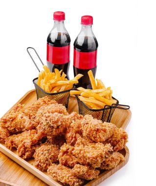 Bir tabakta iki sepet dolusu altın patates kızartması ve iki şişe meşrubatla birlikte bol miktarda kızarmış tavuk var..