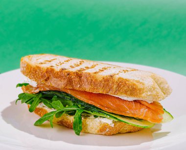 Taze yapılmış bir sandviç katmanları tütsülenmiş somon ve kıtır salatalık, hepsi kızarmış ekmek dilimlerinin arasına yerleştirilmiş. Arugula acı bir dokunuş ekliyor, tadını arttırıyor..