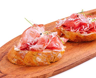 İnce dilimlenmiş et ile kaplı iki dilim kabuklu ekmek ahşap bir tahtada sunuluyor. Bu lezzetli yemek, iyi bir aşçılık ve tazelik sergiliyor..