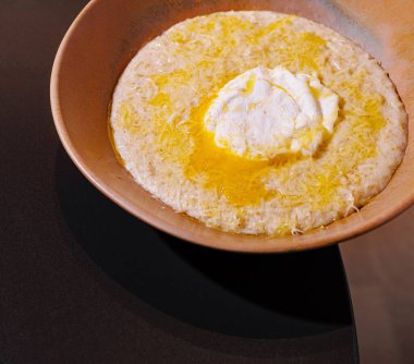 Haşlanmış yumurta, erimiş tereyağı ve rendelenmiş peynir ile kaplanmış kremalı polenta.