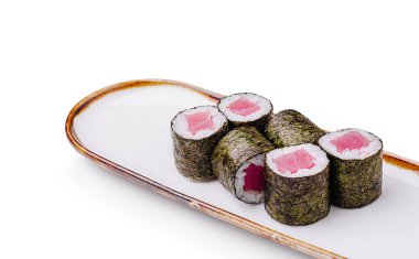 Taze ton balığı ve pirinçle dolu lezzetli suşi ruloları şık beyaz bir tabakta düzenlenir, canlı renkler ve usta işçilik sergilenir. Hafif bir yemek veya atıştırmalık için mükemmel..