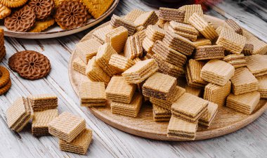 Büyük ahşap bir tabak çeşitli tatlarda çıtır çıtır gofret atıştırmalıklarıyla doludur. Etrafında farklı tipte kurabiyeler var. Şeker toplama için mükemmel..