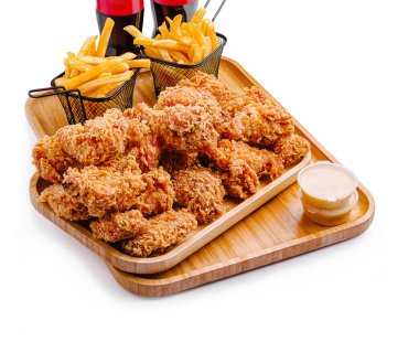 Altın patates kızartması ve alkolsüz içeceklerle birlikte cömert bir tabak kızarmış tavuk sunuluyor. Yemek ahşap bir tepside sunuluyor, lezzetli bir ziyafet sunuluyor..