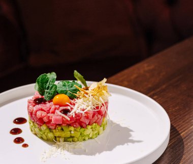 Taze yumurta sarısı, yeşillik ve sosla süslenmiş, beyaz tabakta ince ince doğranmış canlı bir yemek sergisi davetkar bir sunum yaratıyor..