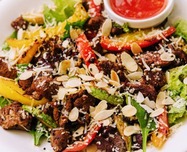 Dilimlenmiş mango, fındık ve soslu sağlıklı et salatası.