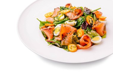 Taze yeşillik, kiraz domatesleri ve bıldırcın yumurtalarıyla karıştırılmış taze somon dilimli canlı bir salata sağlıklı ve çekici bir yemek sergiliyor..