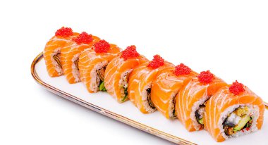 Taze somon dilimleri ve parlak kırmızı havyarla kaplı renkli suşi ruloları beyaz bir tabakta güzelce düzenlenir. Yemeklerde canlı malzemeler ve usta işçilik vurgulanıyor.