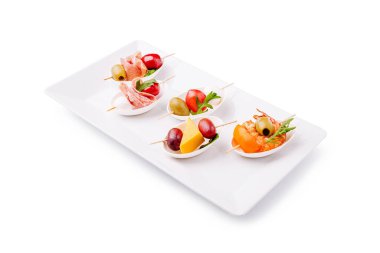 Beyaz bir tabakta düzgünce dizilmiş çeşitli tapalar et, zeytin ve meyveler içerir. Toplanma için idealdir, bu küçük ısırıklar renkli ve şenlikler sırasında eğlenmeye hazırdır..