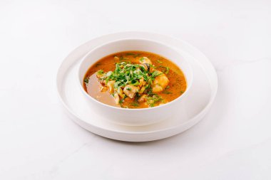 Canlı bir çorba kasesinde yumuşak hamur tatlısı ve taze bitkiler serpiştirilir. Yemek basit beyaz bir tabakta zarif bir şekilde sunuluyor, iştah açıcı renkleri vurgulanıyor..