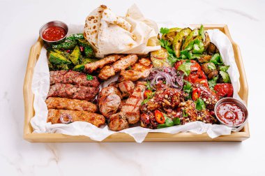 Cömert bir tabak ızgara et kebap, tavuk ve sosis ile birlikte taze sebze ve soslar içerir. Bu iştah açıcı ziyafet için sizi davet ediyor..