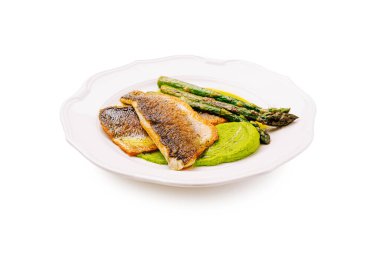 Tavada kurutulmuş balık filetosu içeren bir gurme tabağı. Canlı yeşil püre ve taze kuşkonmazla eşleştirilmiş. Zarif bir şekilde saf beyaz bir tabakta sıralanmış. Güzel yemekler için mükemmel..