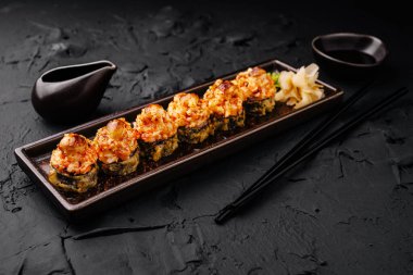 Koyu dokulu bir masada deniz ürünleri içeren güzel bir suşi tabağı servis edilir. Yanında zencefil ve soya sosu ile birlikte mutfaktaki lezzeti de davet eder..