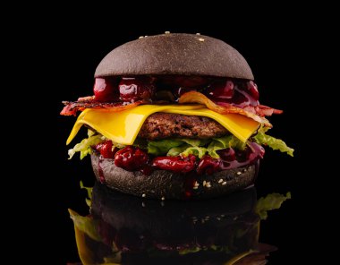 Bu siyah hamburgerde kıtır kıtır pastırma, erimiş peynir, taze marul ve canlı soslar var. Yansıtıcı bir yüzeyde, alışılmadık tasarımını vurgulayan karanlık bir zemin ile sunuluyor..