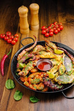 Taze domates ve baharatların yanında ızgara karides, ahtapot ve balık içeren canlı bir deniz ürünleri tabağı. Bu lezzetli yemek, şenlikli bir toplantıda paylaşmak için mükemmel..