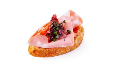 Lezzetli bir sunum için kurutulmuş domatesler ve taze otlarla süslenmiş çıtır ekmek diliminde meze katmanları sunan gurme bir sandviç tabakası..