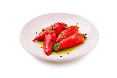 Lezzetli bir dolguyla doldurulmuş üç canlı kırmızı biber beyaz bir tabakta duruyor. Taze bitkilerle süsleniyorlar ve hafif zeytinyağı serpiştiriyorlar. Bu da iştah açıcı bir sunum oluşturuyor..