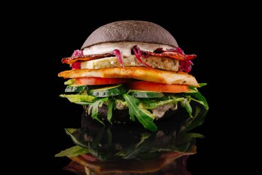 Bu gurme burger ızgara tavuk, taze sebze ve özel soslarla dolu bir siyah çörek içerir. Geleneksel fast food 'a yaratıcı bir yaklaşımın altını çiziyor..